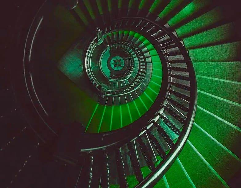 Looking down a green-lit spiral staircase